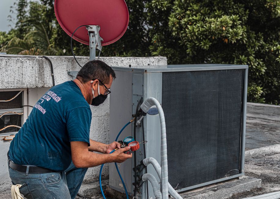 Técnico realizando manutenção em equipamento de ar-condicionado em espaço externo de edifício comercial.