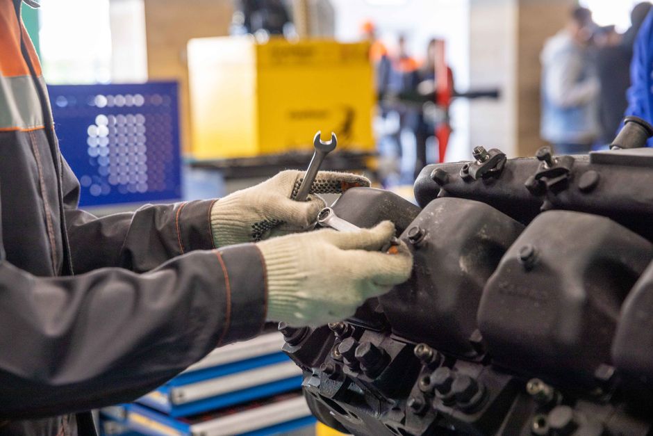 Homem realizando manutenção em um motor de automóvel na oficina, evidenciando o trabalho técnico com veículos.