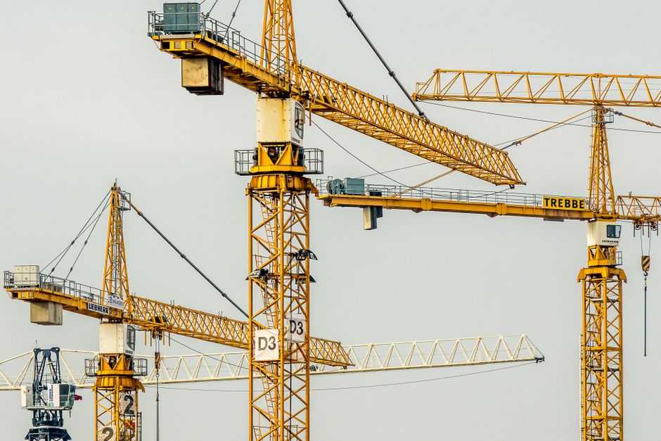 Imagem de dois guindastes de construção civil, simbolizando crescimento e desenvolvimento de projetos de engenharia ou obras de grande porte.