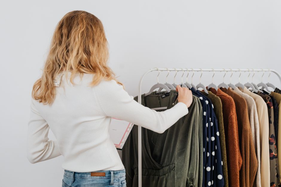 Mulher escolhendo roupas de um cabideiro, representando moda, estilo ou compras