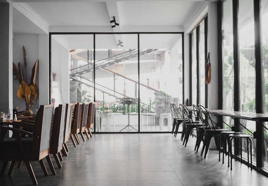 Ambiente minimalista de um espaço de coworking com grande área de janelas de vidro, ideal para trabalho colaborativo e reuniões.