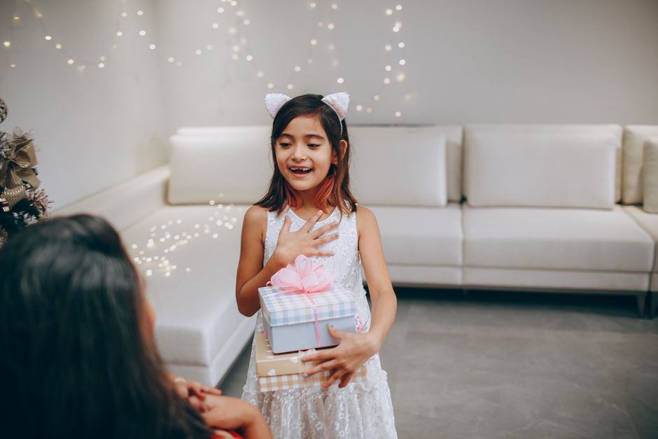 Criança recebendo um presente em uma celebração, transmitindo entusiasmo e alegria.