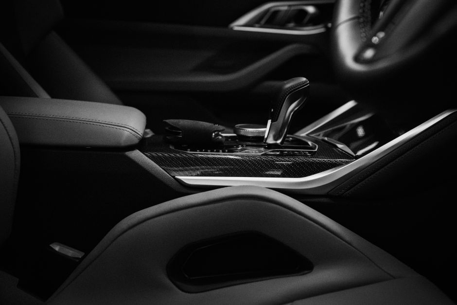 Interior de um carro moderno com foco na transmissão automática e detalhes em acabamento esportivo, ideal para artigos sobre tecnologia veicular e automobismo de luxo.