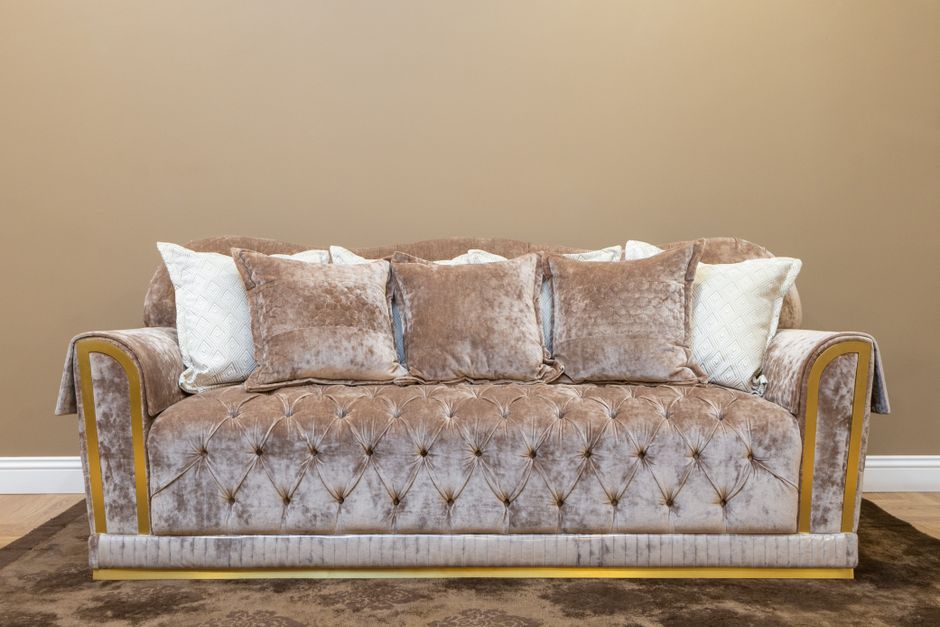 Sofá de veludo com almofadas em um ambiente de sala de estar, transmitindo conforto e elegância ao espaço.