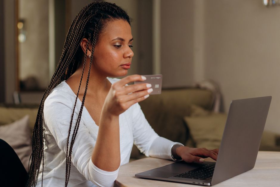 Mulher realizando uma compra online usando um cartão de crédito, com foco na facilidade de compras digitais.