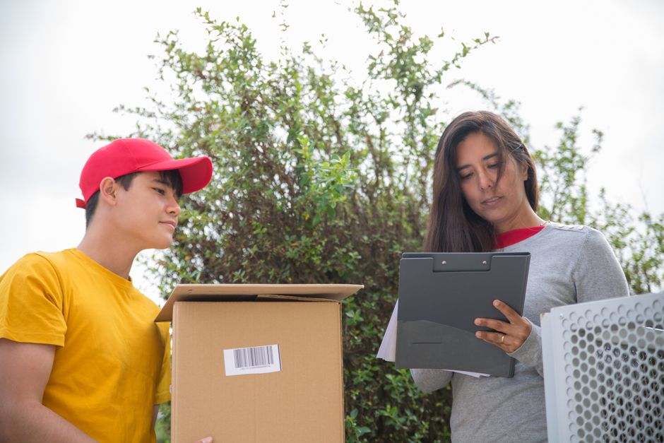 Mulher e jovem entregando uma encomenda ao ar livre, simbolizando serviços de entregas e logística.