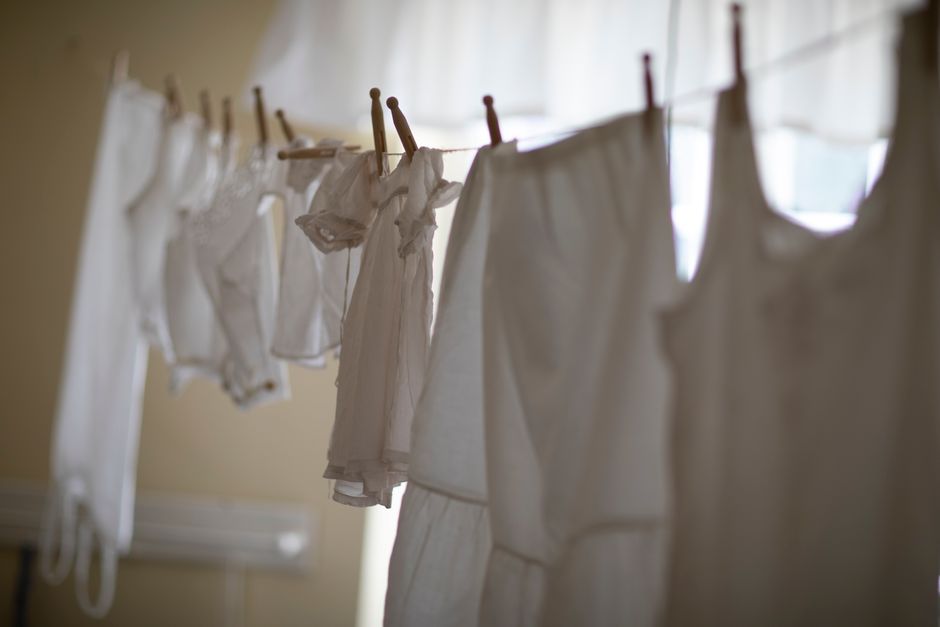 roupas brancas penduradas para secar em uma área com iluminação natural, refletindo a rotina de cuidar da casa ou lavanderia