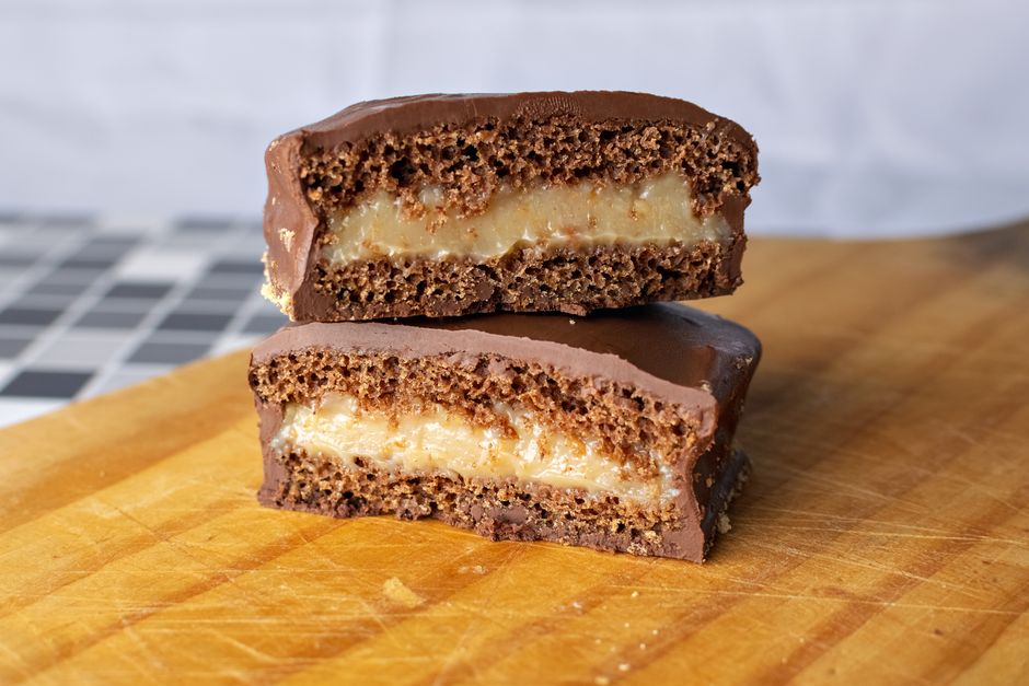 Imagem de um biscoito recheado de creme com cobertura de chocolate, ideal para ilustrar conteúdo sobre doces, lanches ou confeitarias.