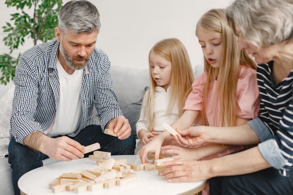 Uma família reunida jogando dominó em casa, promovendo momentos de convivência e diversão em família.