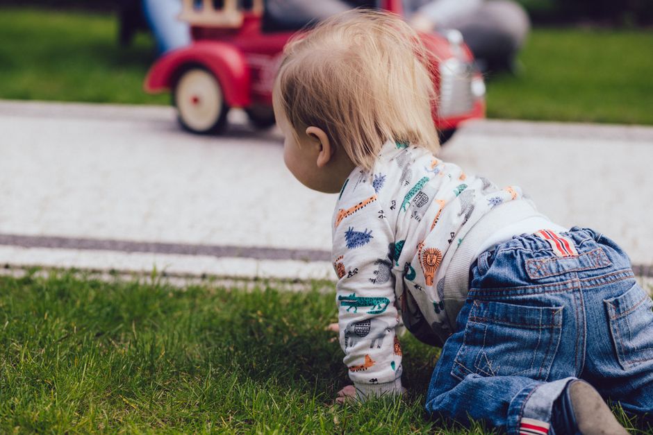 Criança brincando ao ar livre em um parque, explorando o ambiente no chão.