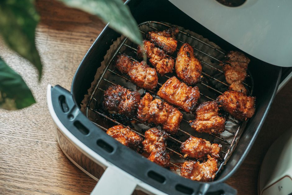 Imagem de asinhas de frango sendo preparadas na air fryer, ideal para um artigo sobre culinária saudável ou receitas de petiscos.