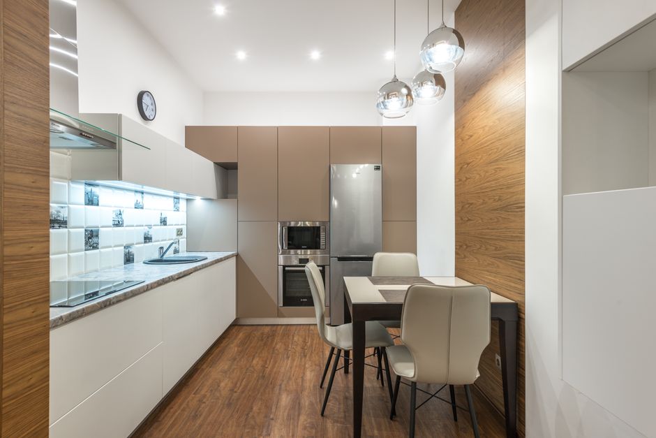 Imagem de uma cozinha moderna com mobiliário minimalista, iluminação sofisticada e revestimentos de madeira, ideal para um blog sobre decoração de interiores ou organização residencial.