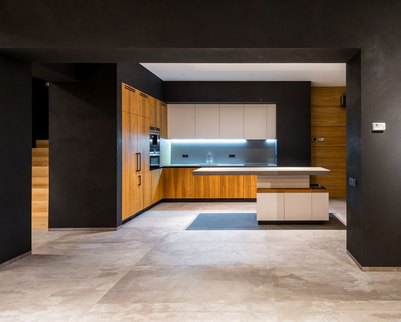 Imagem de uma cozinha moderna com combinações de cores neutras, armários de madeira e iluminação embutida, evidenciando design contemporâneo e funcionalidade.