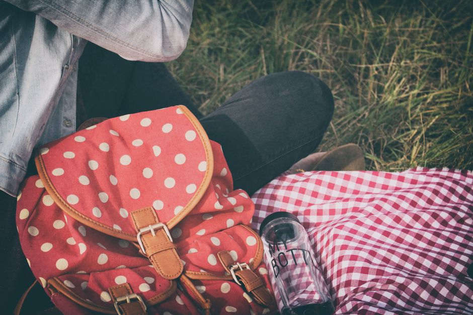 Pessoa descansando ao ar livre com mochila e garrafa de água, simbolizando lazer e conexão com a natureza.