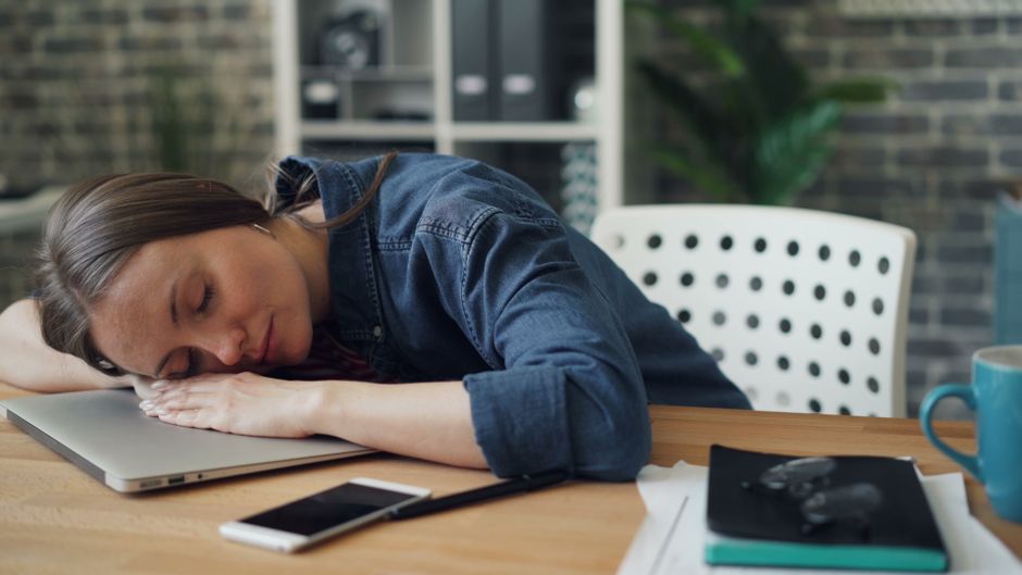 Pessoa cansada e exausta após um longo dia de trabalho, descansando na mesa de escritório.