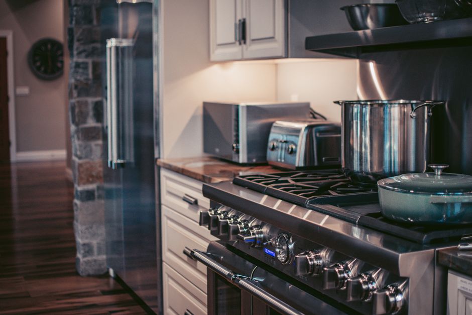 Imagem de uma cozinha moderna com fogão de inox e utensílios de cozinha, destacando um ambiente residencial aconchegante e bem equipado.