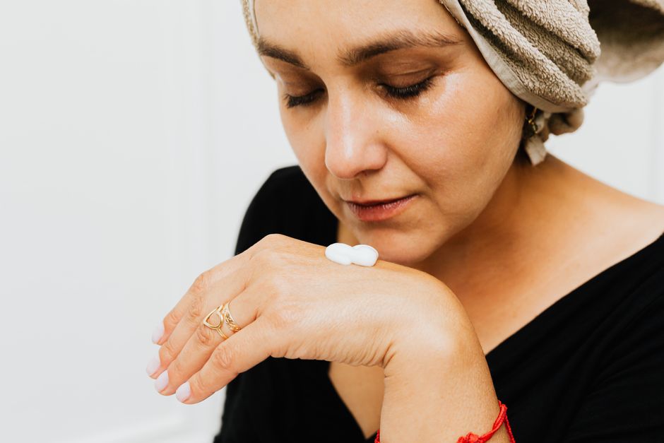 Mulher aplicando creme no rosto, focando no cuidado com a pele e rotina de beleza feminina.