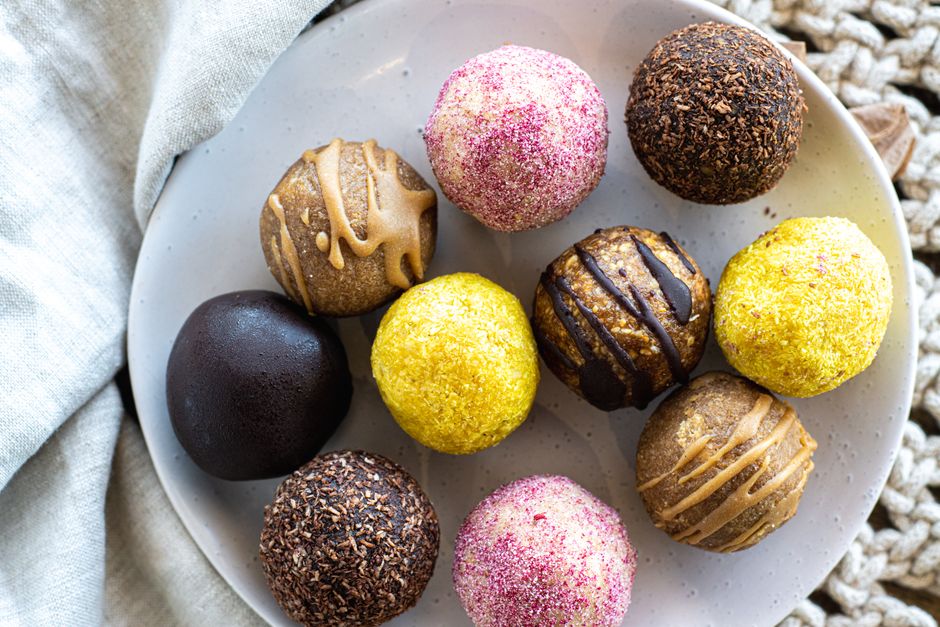 Imagem de uma variedade de bolinhas doces decoradas em uma travessa, ideal para ilustrar artigos sobre gastronomia, doces artesanais ou festas.