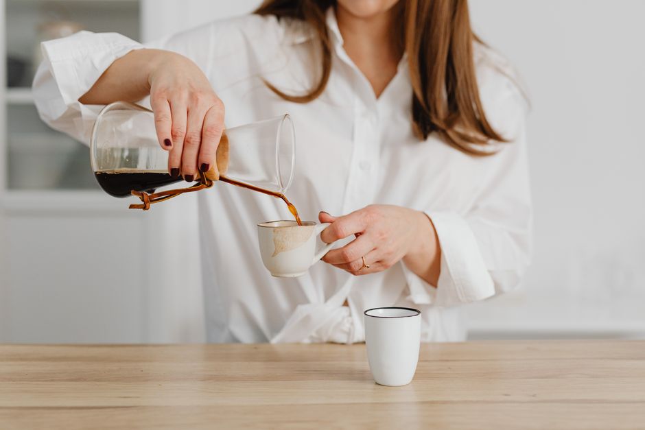 Mulher preparando um café na cozinha, simbolizando rotina matinal e momento de pausa.