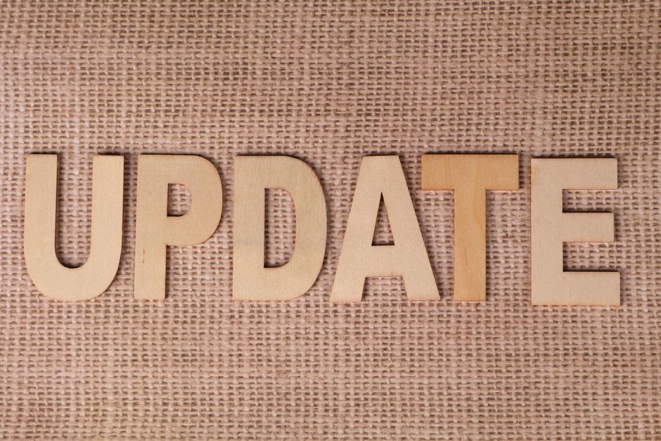 Imagem com letras de madeira formando a palavra 'UPDATE' sobre uma superfície de tecido, simbolizando atualização ou mudança.