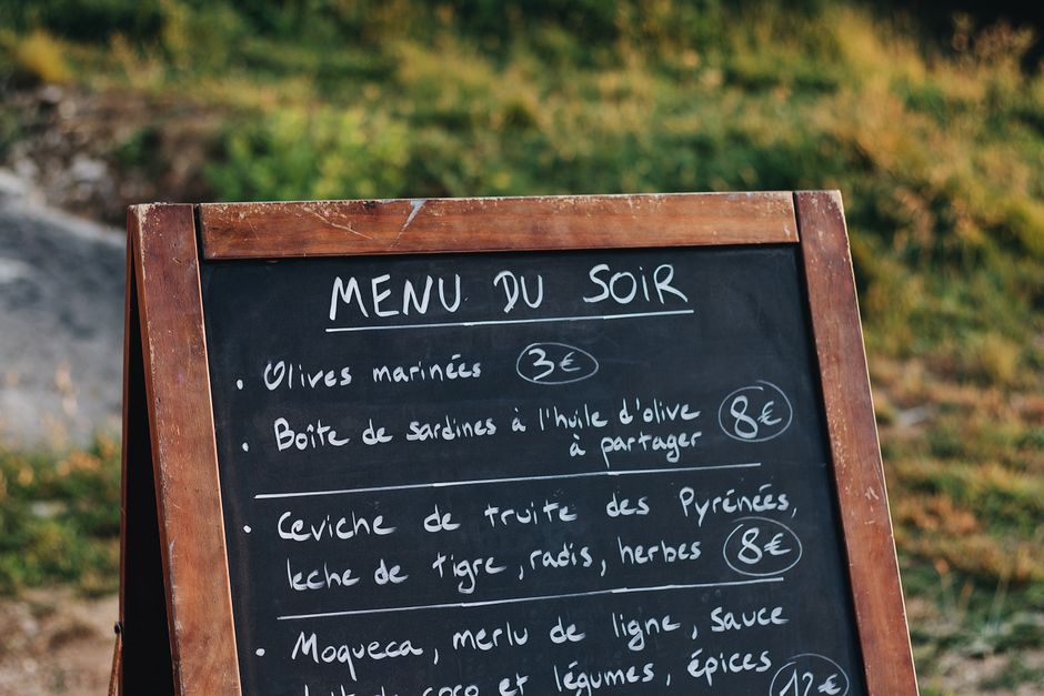Quadro de cardápio fotográfico com opções de jantar de um restaurante em ambiente ao ar livre.