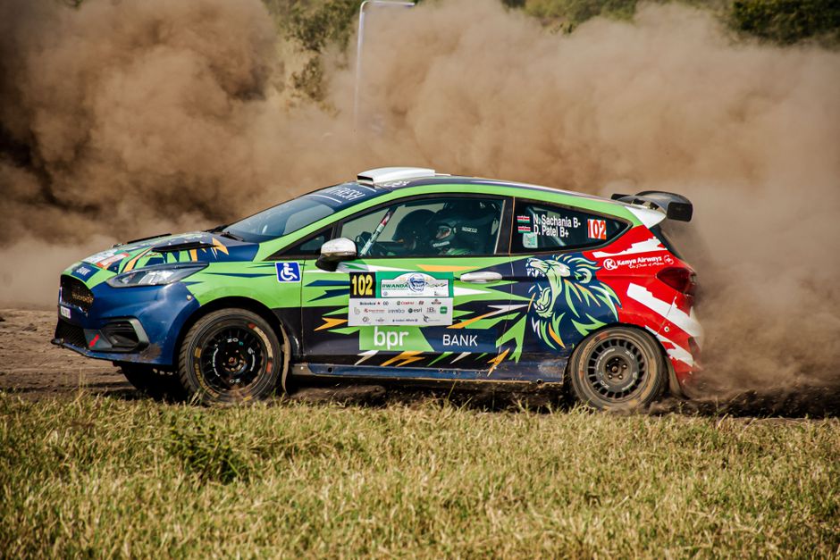 Carro de rali em alta velocidade, realizando uma manobra com poeira levantando do solo, representando adrenalina e desempenho esportivo.