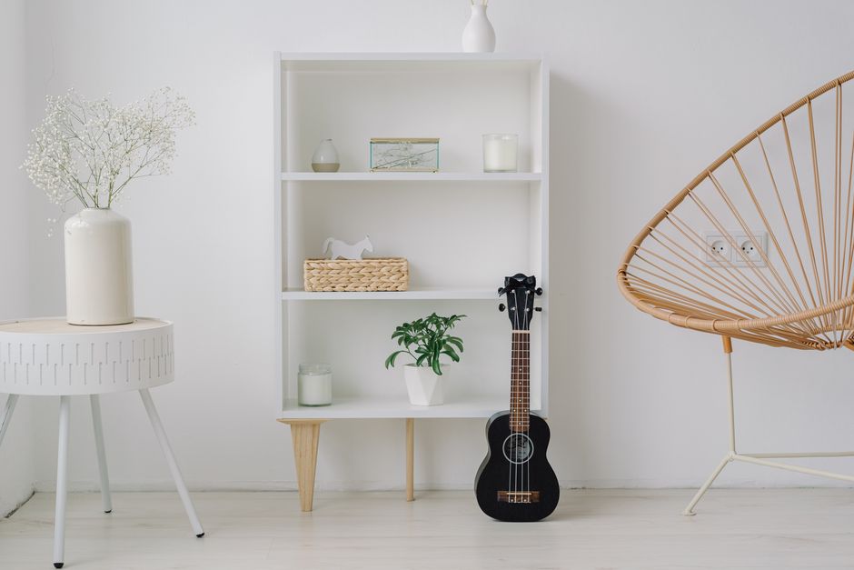 Imagem de um ambiente minimalista e aconchegante com decoração clara, uma prateleira com objetos decorativos e uma guitarra, ideal para blogs sobre decoração de interiores e estilo de vida.