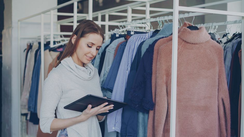 Mulher fazendo uma análise de inventário de roupas em uma loja de moda ou boutique.