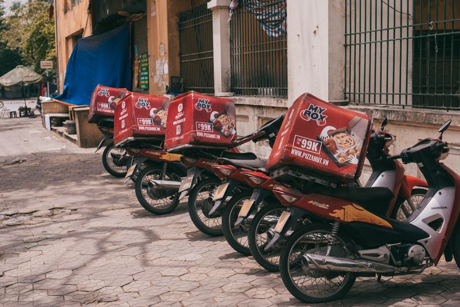 Linha de mototáxis com entregadores aguardando clientes em ambiente urbano, mostrando a mobilidade por mototáxi para transporte de pedidos.