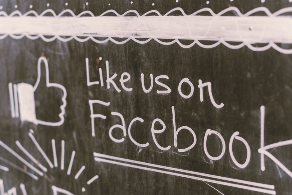 Quadro de giz em lousa com mensagem promocional do Facebook e elementos gráficos relacionados às redes sociais.