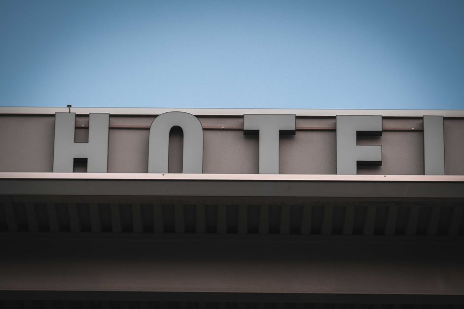Fachada de um hotel com sinalização visível contra um céu claro, representando hospedagem e turismo.