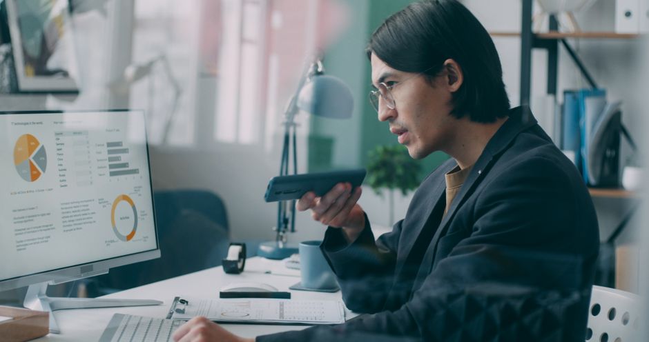 Homem no escritório analisando dados financeiros exibidos em tela, com foco na gestão e estratégia empresarial.