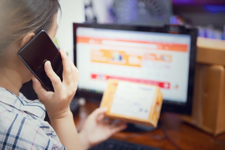 Pessoa realizando compras online enquanto consulta uma tela de computador, ilustrando o tema de comércio eletrônico e tecnologia de compras digitais.