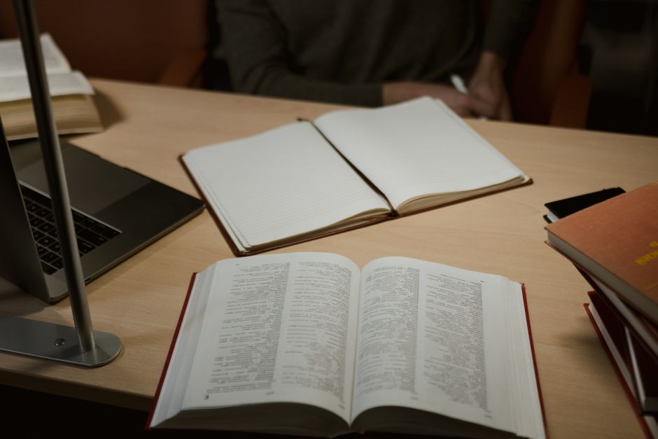 Estação de estudos com livros abertos, caderno e laptop, ideal para artigos sobre pesquisa e preparação acadêmica ou profissional.