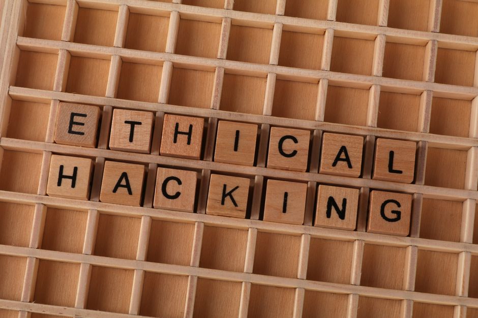 Imagem com blocos de madeira formando a palavra 'ÉTICA' acima da palavra 'HACKING', sugerindo reflexão sobre ética no contexto da segurança cibernética.
