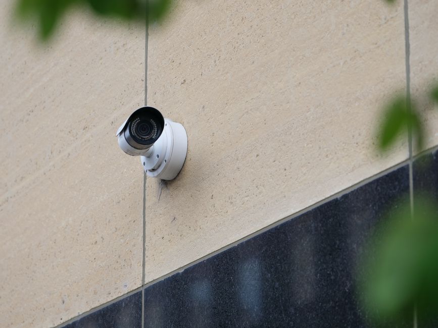Câmera de segurança instalada na parede externa de um edifício, simbolizando vigilância e segurança urbana.