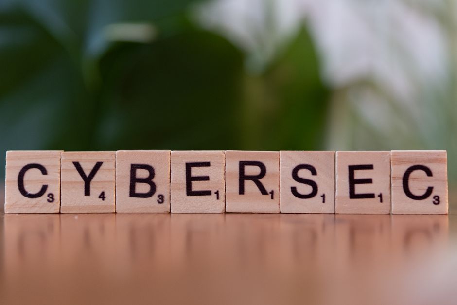 Imagem com blocos de madeira formando a palavra 'CYBERSEC', representando segurança cibernética em um contexto digital.