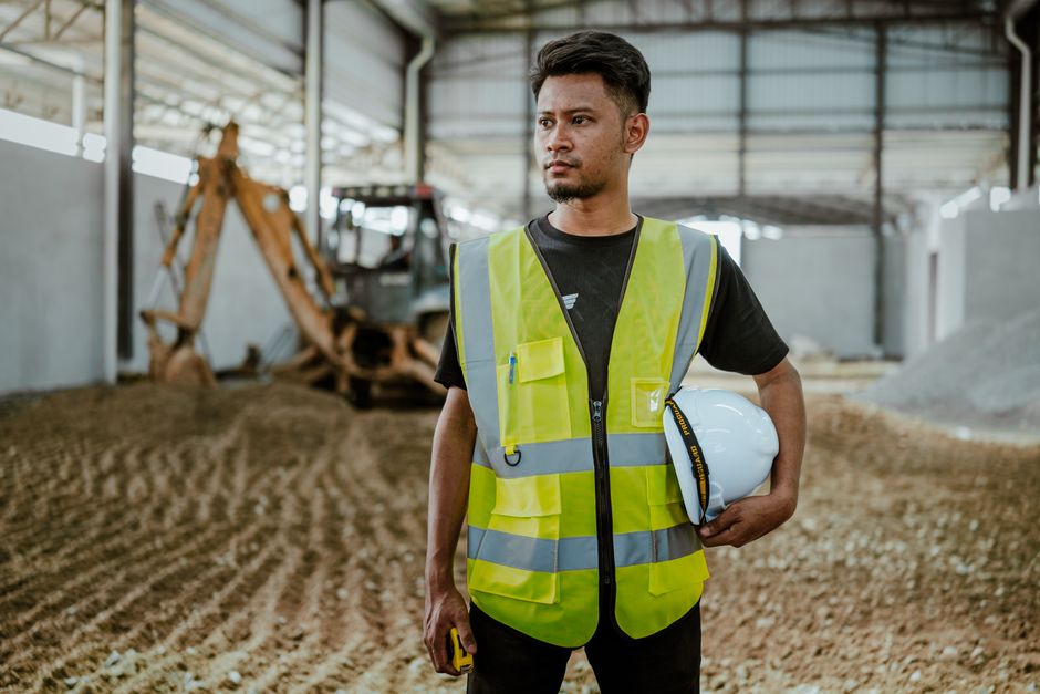 Homem engenheiro ou supervisor em uma obra de construção civil, avaliando o progresso do projeto.