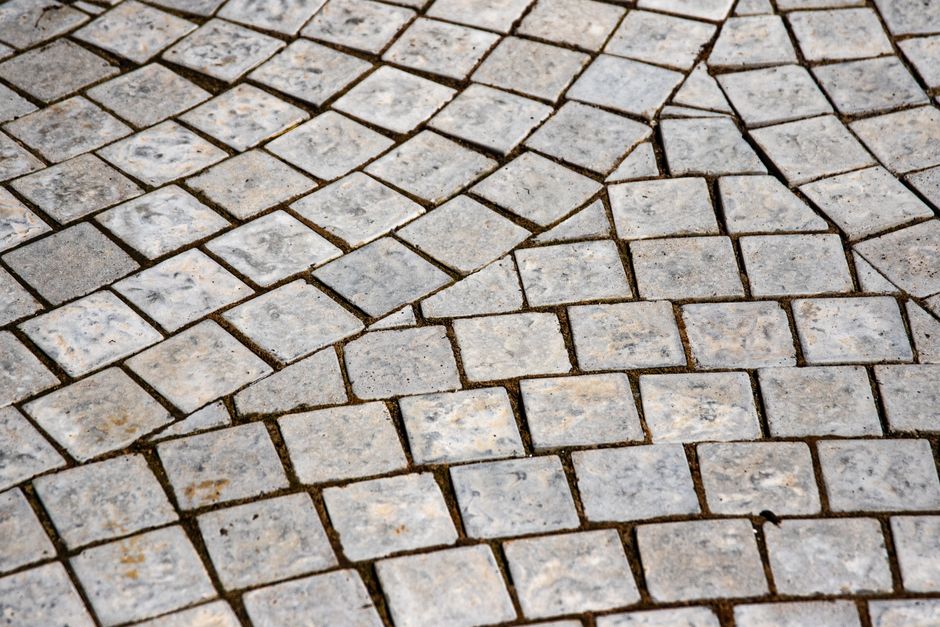 Imagem de calçamento em pedra, destacando a textura e o padrão irregular das pedras, ideal para ilustrar temas relacionados a pavimentação, calçadas ou infraestrutura urbana.