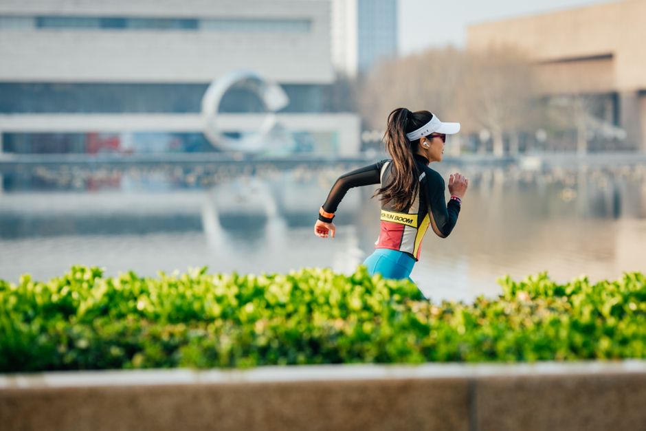 Imagem de uma mulher correndo ao ar livre em um parque urbano, simbolizando saúde, bem-estar e estilo de vida ativo.