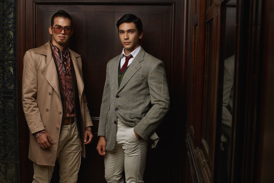 Homens vestindo roupas sofisticadas em ambiente elegante, transmitindo uma atmosfera de poder e estilo clássico.