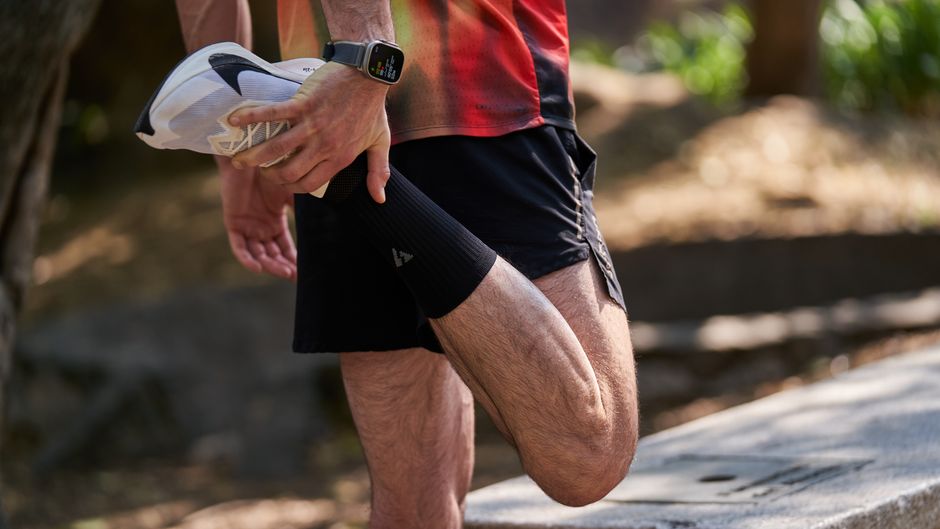 Homem realizando alongamento ou exercício físico ao ar livre, simbolizando saúde, bem-estar e preparação para atividades físicas.