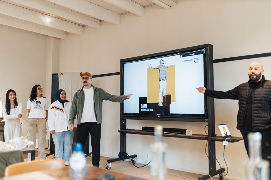 Grupo diversificado participando de uma apresentação ou treinamento corporativo com uso de tecnologia digital em um ambiente de sala de reuniões.