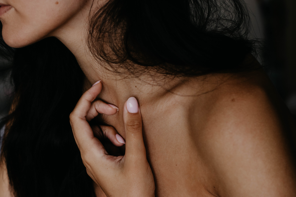 Mulher com expressão de dor ou desconforto, segurando o pescoço, representando questões relacionadas à saúde ou bem-estar.