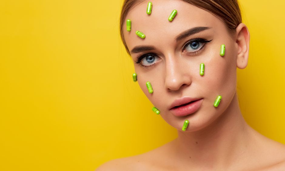 Imagem artística de uma mulher com cápsulas verdes espalhadas pelo rosto, simbolizando cuidados com a saúde ou bem-estar.