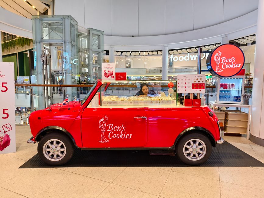 Carrinho de venda de biscoitos decorado com tema clássico, localizado dentro de shopping center, promovendo produtos artesanais.