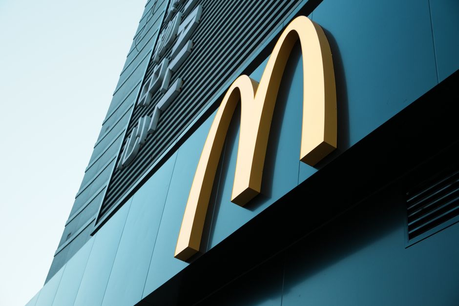 Fachada de uma loja McDonald's, destacando seu logo em um prédio comercial moderno.