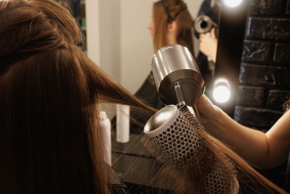 Profissional de beleza secando cabelo de uma cliente em sala de beleza ou salão de estética.