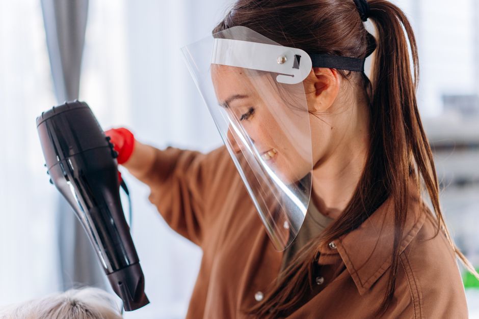 Profissional de saúde usando equipamento de proteção enquanto realiza procedimento clínico em ambiente de saúde.
