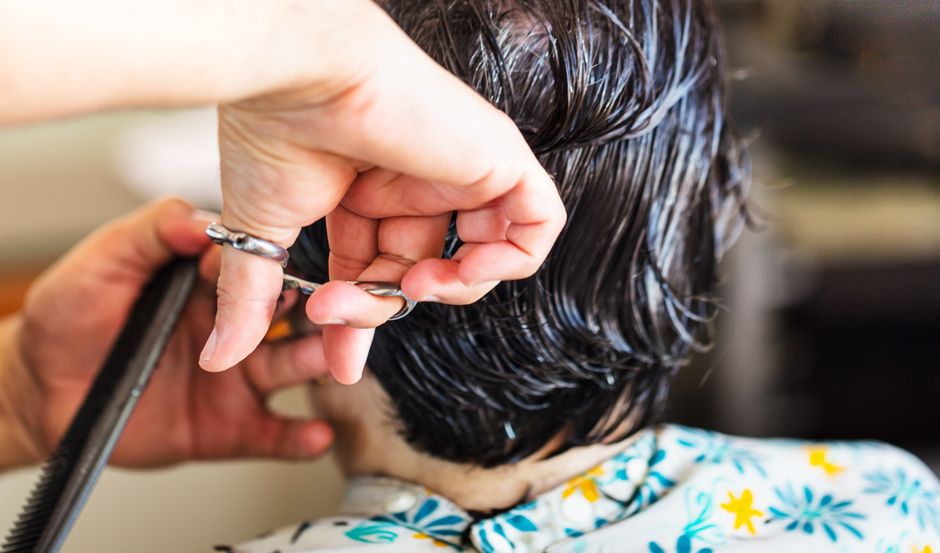 Pessoa cortando o cabelo de um cliente em um salão de beleza, focando no serviço de cabeleireiro.